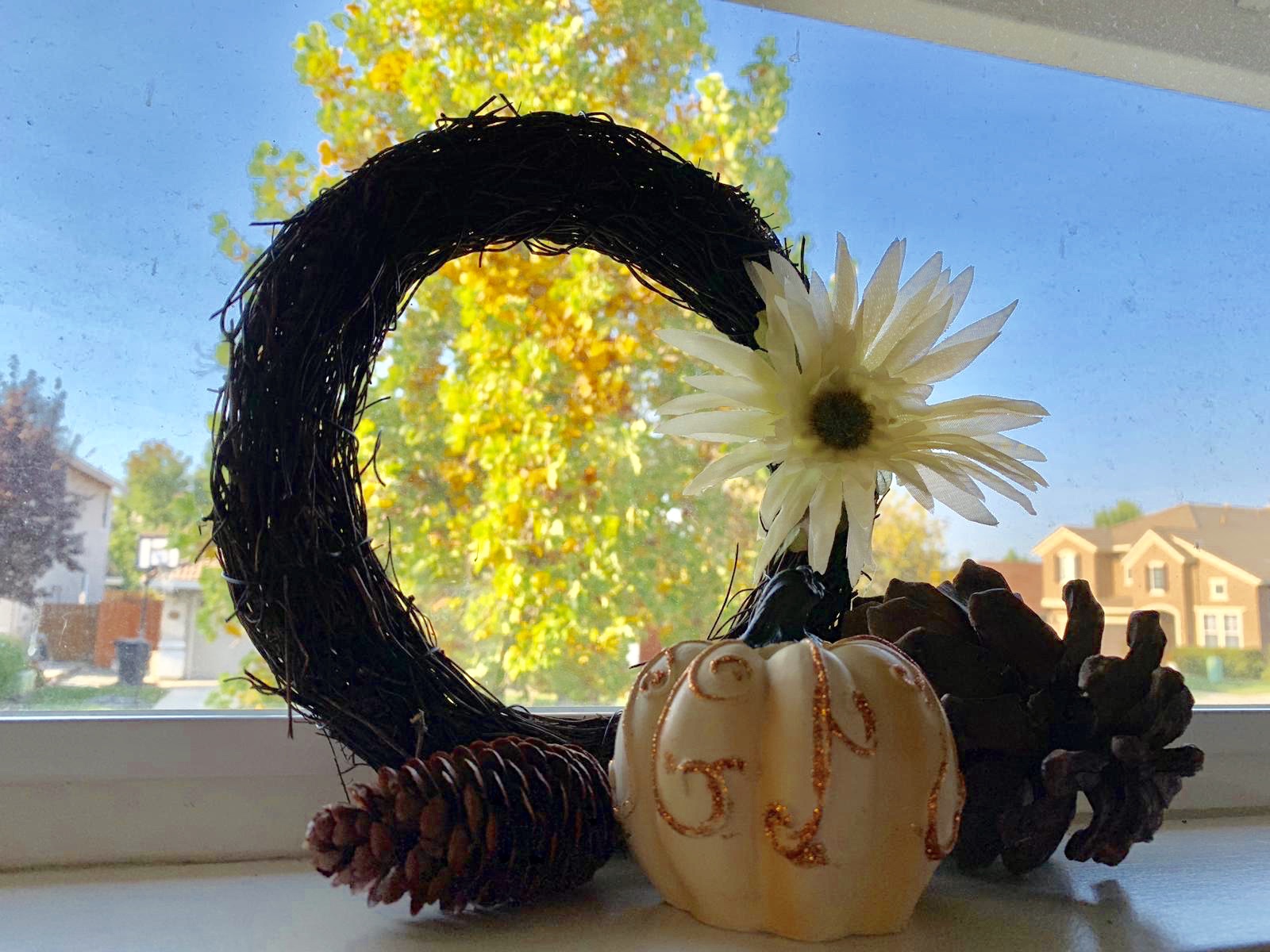 Wreath with a seasonal flower, decorated mini-pumpkin and some pine ones.